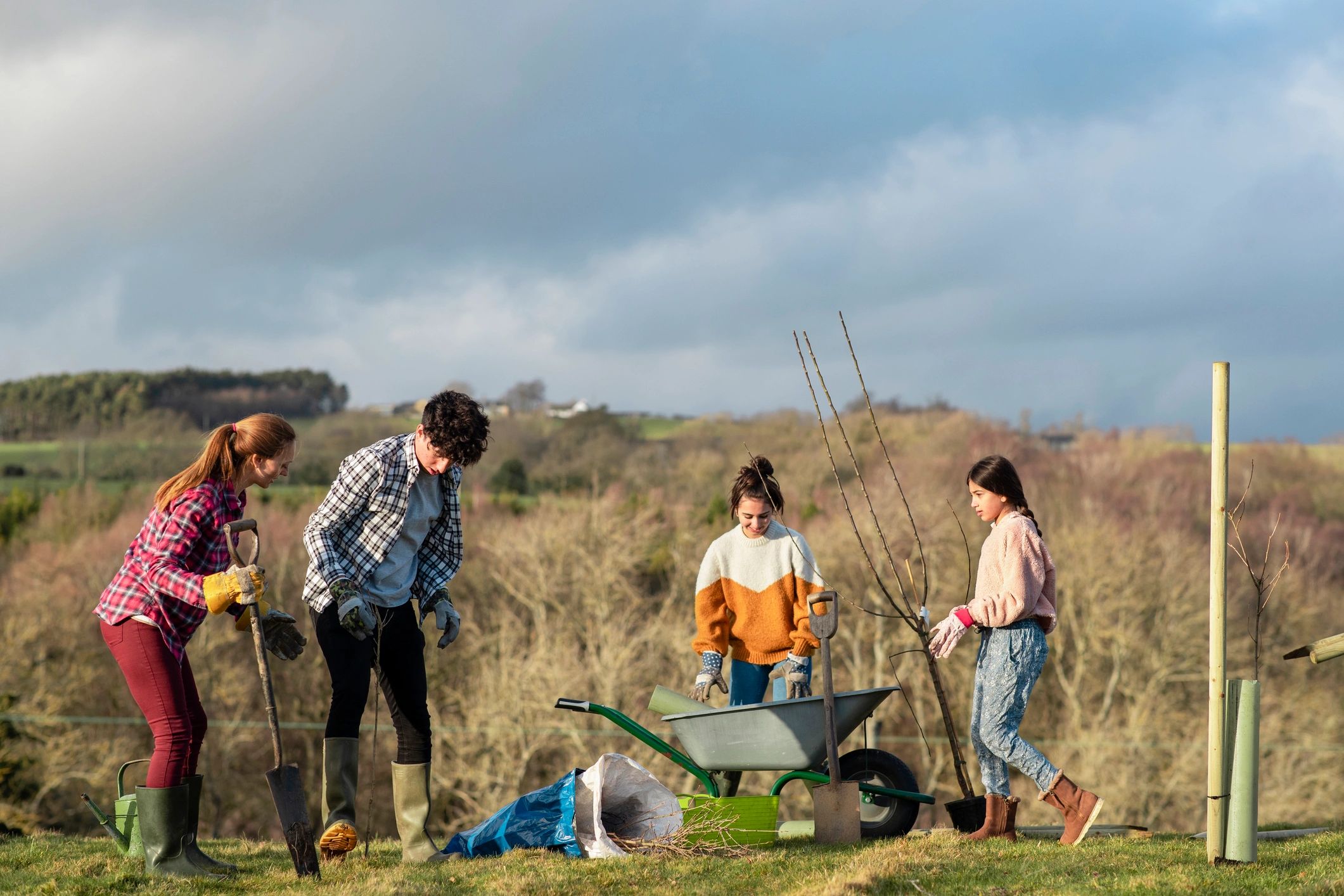Family and volunteers planting a tree together